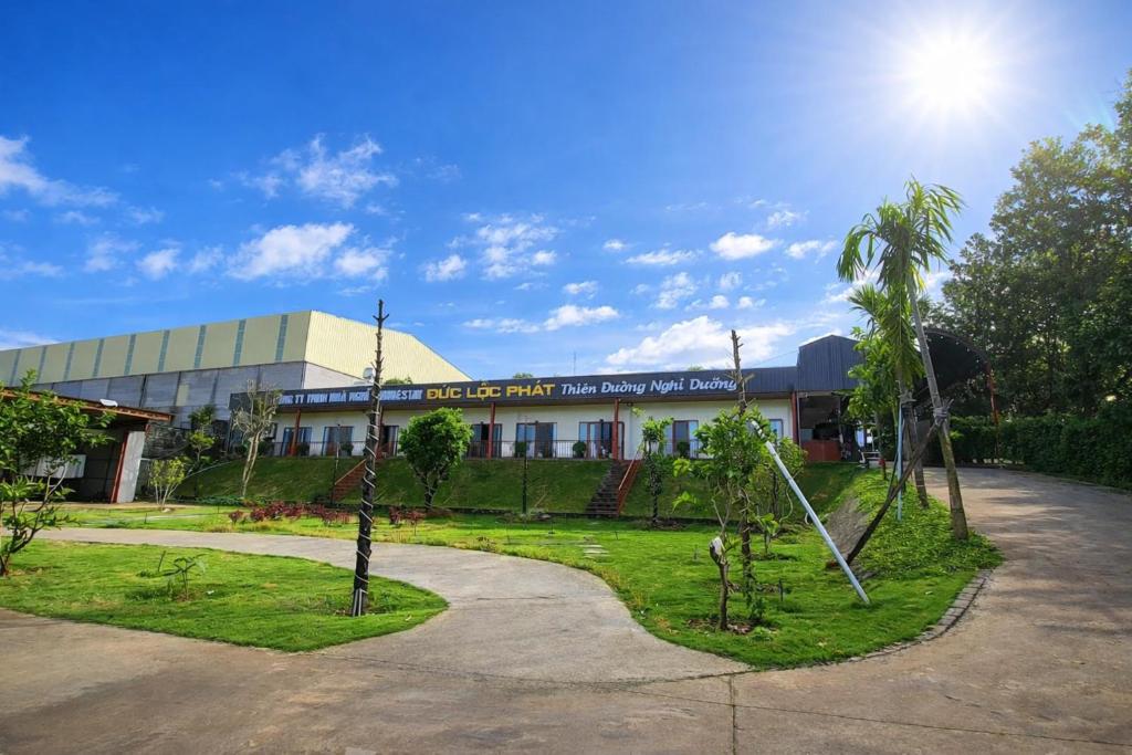 a building with a courtyard with trees in front of it at Khách sạn Đức Lộc Phát in Kiến Ðức