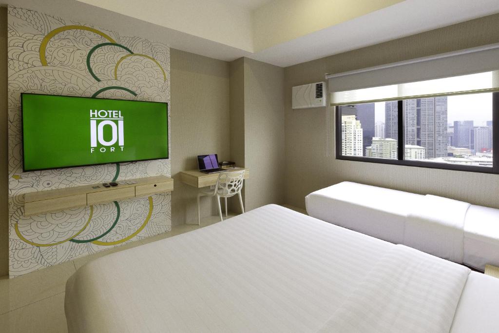 a hotel room with a bed and a tv on a wall at Hotel101 - Fort in Manila