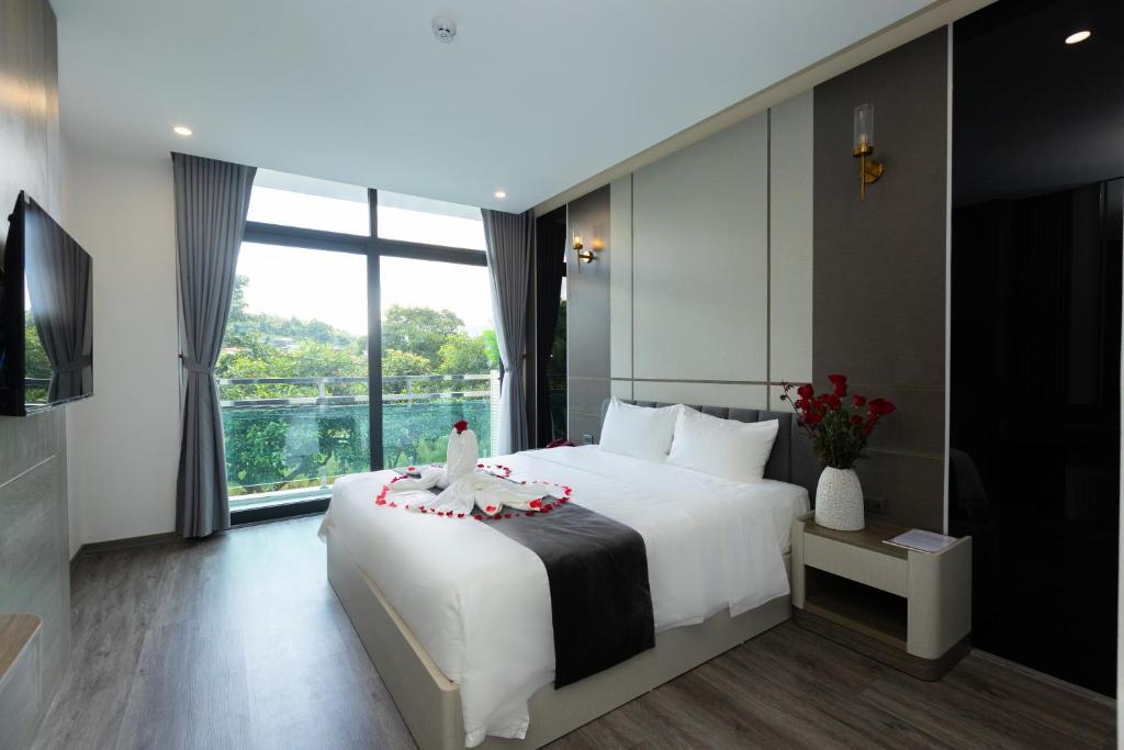a bedroom with a white bed and a large window at NaCo Hotel in Lao Cai