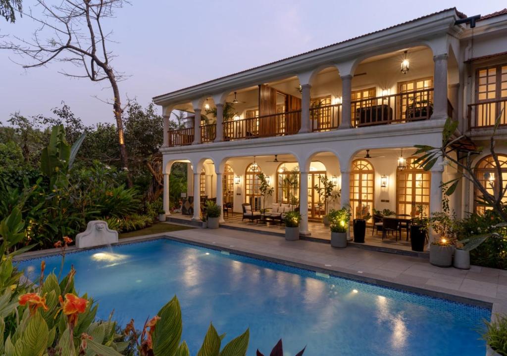an exterior view of a house with a swimming pool at LohonoStays Villa Floresta in Assagao