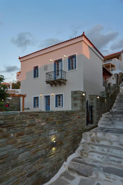 a white house with a balcony on top of a stone wall at Alaia Boutique houses in Batsi