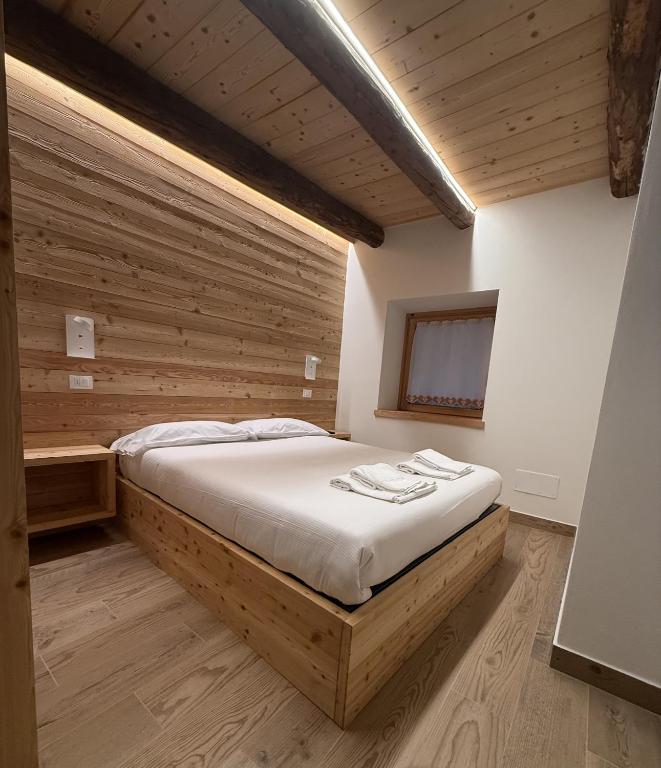 a bedroom with a bed in a room with wooden walls at Mulini 22 - Eco Suite & Spa in Temù