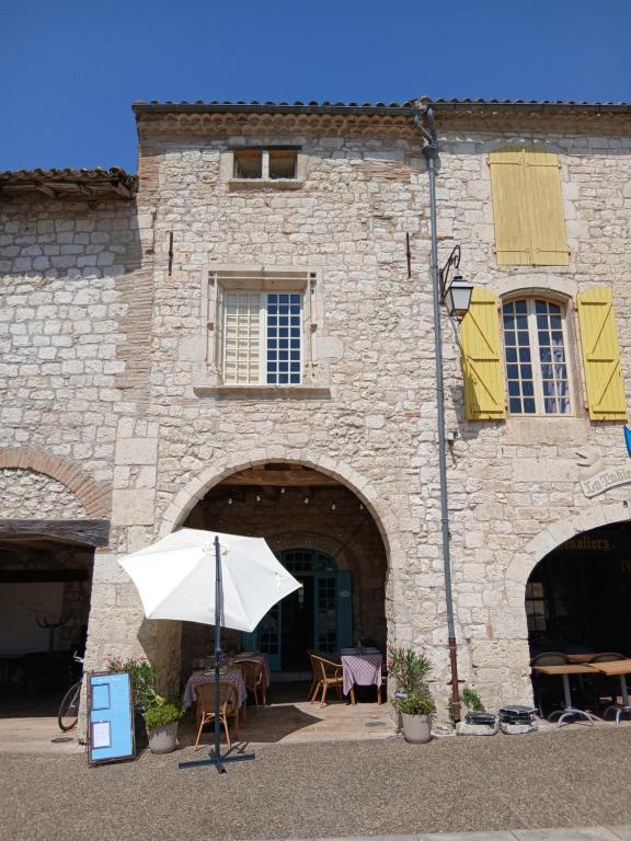 a white umbrella in front of a building at au coin perdu in Lauzerte