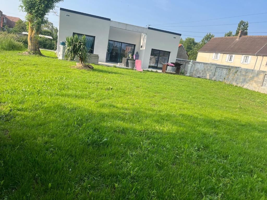 a house in the middle of a field of grass at Normandy lodges in Le Dézert