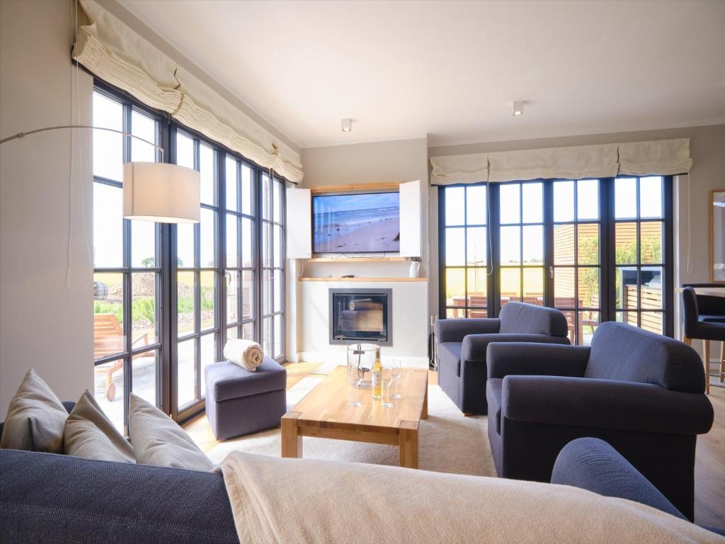 a living room with couches and a fireplace at Reetland am Meer - LuxusPlus Reetdachvilla mit 4 Schlafzimmern, Außensauna, Loungebereich und Kamin H12 in Dranske