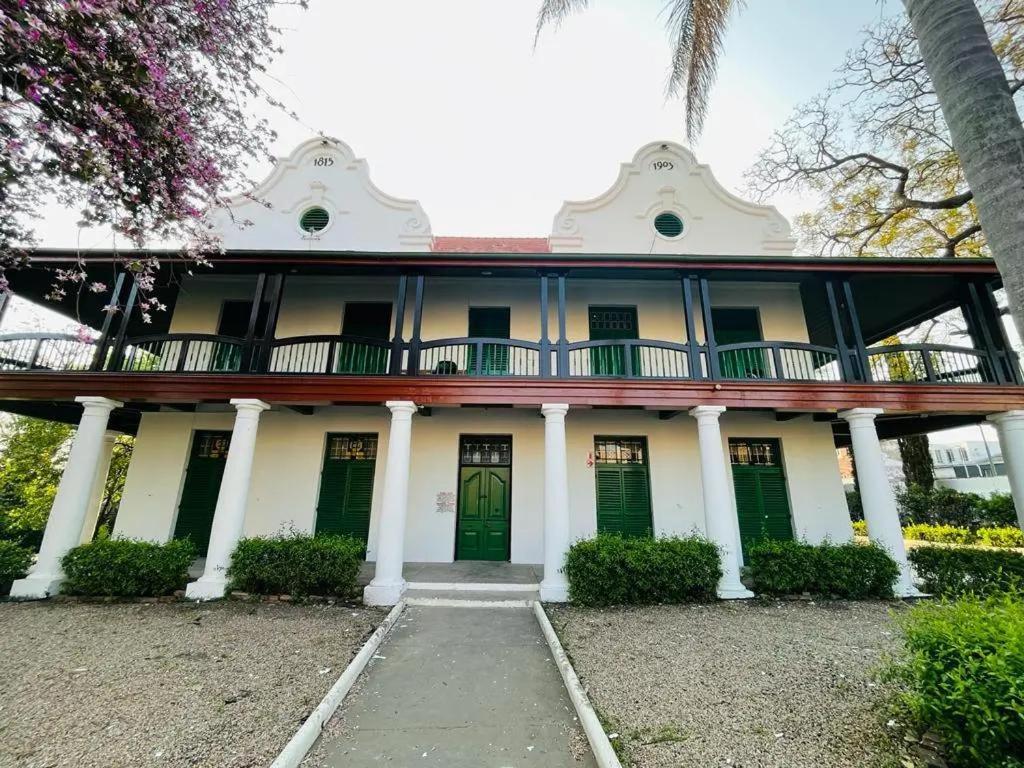 an old house with green doors and trees at HEBA GUEST LODGE in Uitenhage