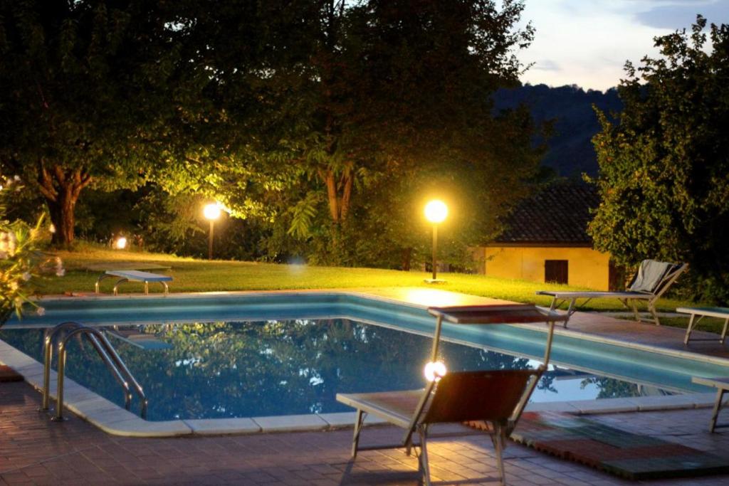 una piscina por la noche con 2 sillas y una mesa en Le Fontane, en Urbino