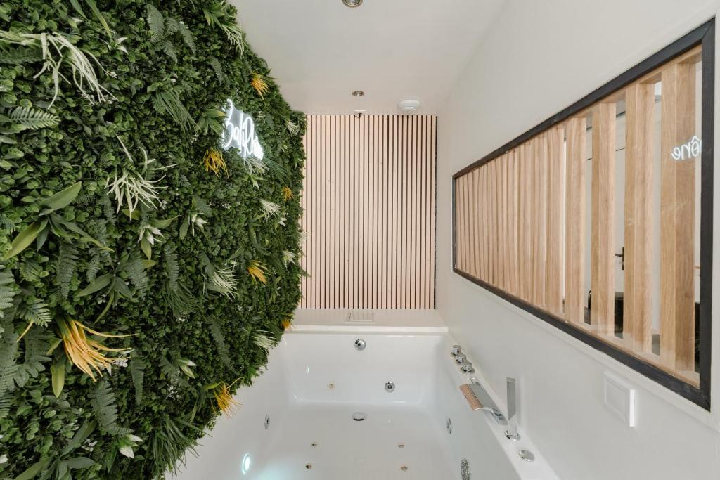 a bathroom with a green wall next to a tub at BaliRhône - Spa privé & balcon avec vue in Tournon-sur-Rhône