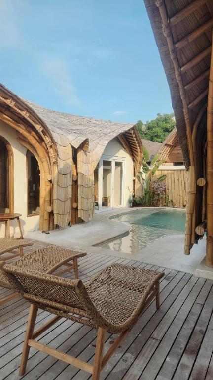 a wicker chair sitting on a deck next to a pool at Sea Turtle Villas in Gili Islands