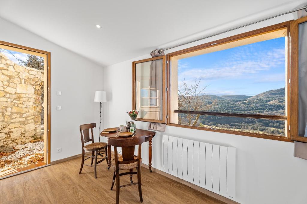 a room with a table and chairs and a large window at Le Cocon de la Combe - Maisonnette pour 4p in Coursegoules