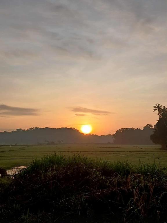 a sunset in a field with the sun in the sky at Villa Rina in Kottagoda