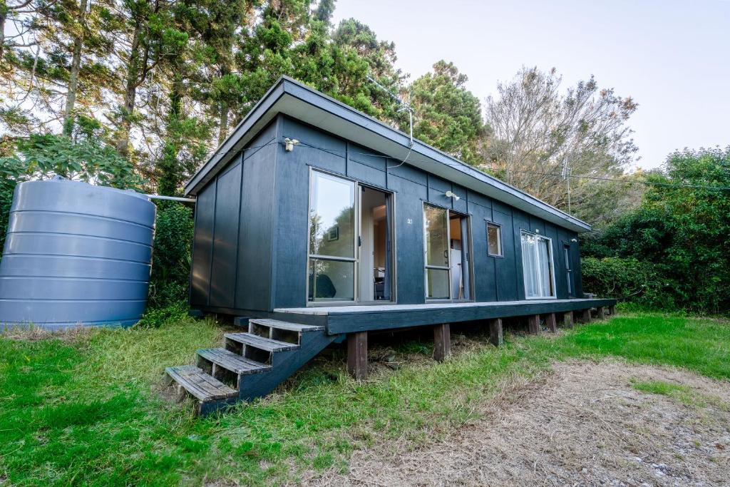 a blue tiny house with stairs next to a barrel at Stoneybrook Cabins in Waimauku