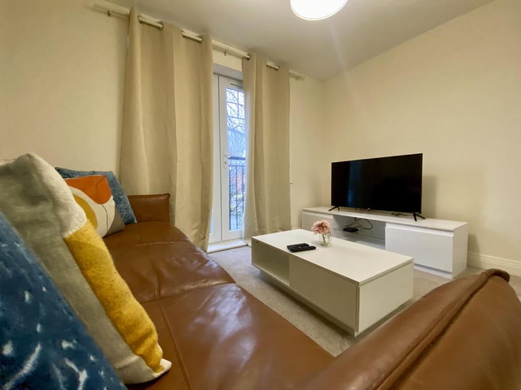 a living room with a couch and a flat screen tv at Wokingham Stylish Two Bedroom Apartment in Wokingham