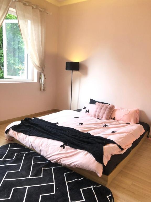 a bedroom with a large bed with pink and black sheets at Nhà 5 PM in Da Thien