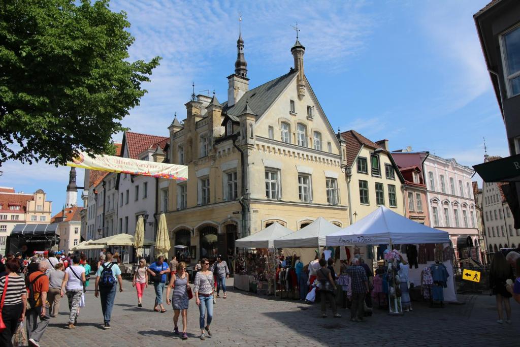 Un gruppo di persone che camminano per una strada di fronte a un edificio di Tallinn City Apartments - Town Hall Square a Tallinn