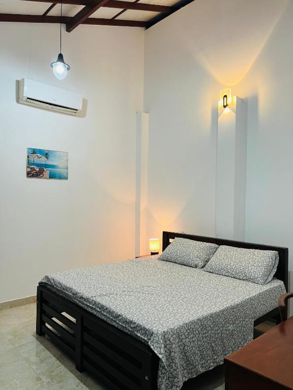 a bedroom with a bed in a white room at Manthraa Holiday Apartment in Ratgama Hegoda