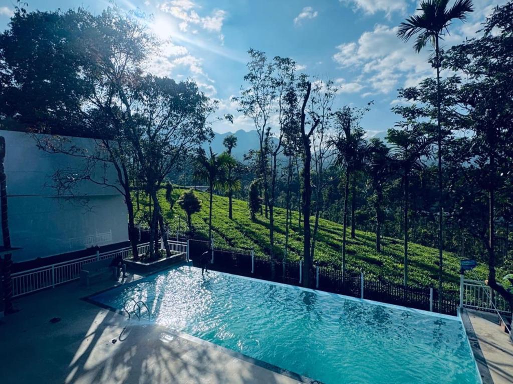 a swimming pool with a view of a field and trees at Hayashi Resort in Meppādi