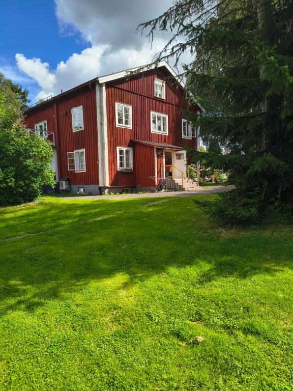 a large red barn with a large green yard at Sunnemoslantliv B&B in Sunnemo