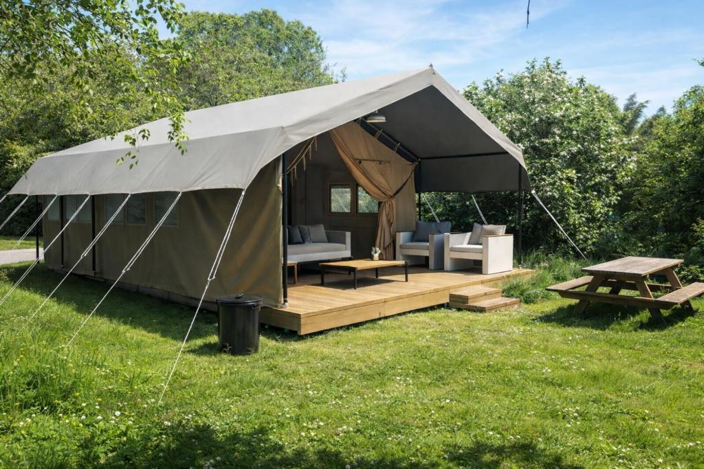 a tent with a picnic table and chairs in a field at Ingerichte safaritent in Saint-Priest-en-Murat