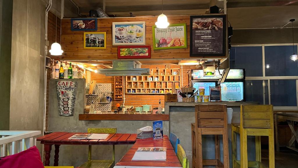 a restaurant with a bar with a counter and tables at Shelter Hostel Malang in Malang