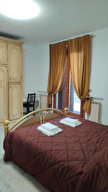 a bedroom with a large bed with red sheets and a window at Villa Bazzera in Mestre