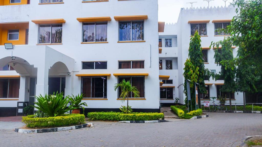 a white building with trees in front of it at Tum Hotel & Conferencing in Mombasa