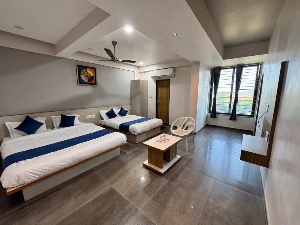 a bedroom with two beds and a table in a room at Hotel Jb Classic in Himatnagar