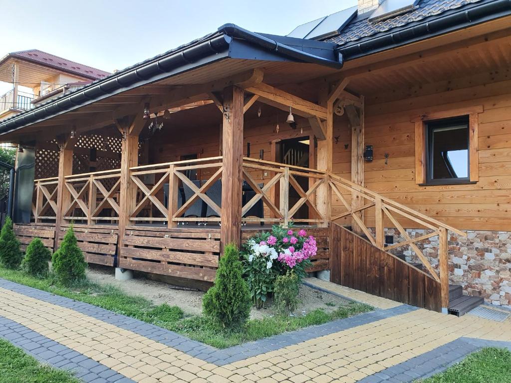 a wooden house with flowers in front of it at Chata Venus in Bóbrka