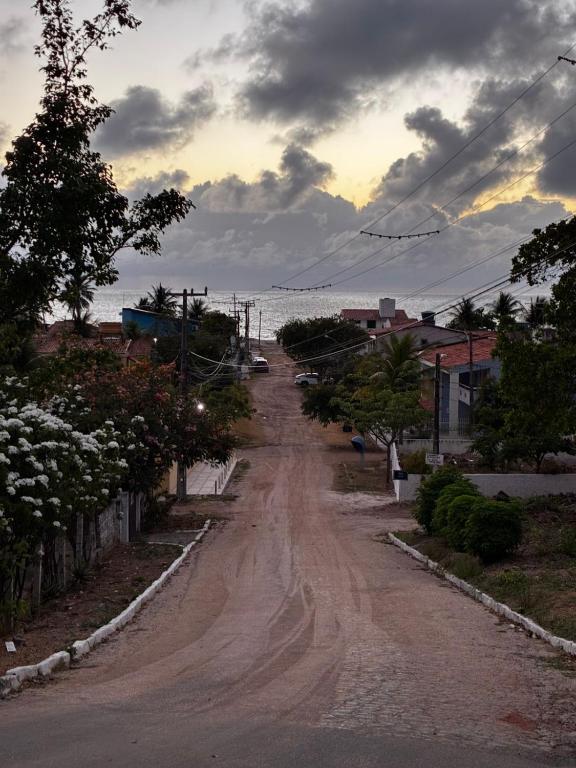 a dirt road leading to the ocean on a cloudy day at Prive Dona Valentina in Itamaracá