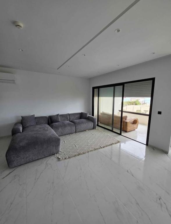 a living room with a couch and a large window at Sousse in El Ahmar