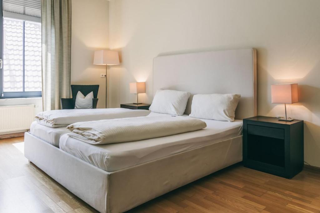 a bedroom with two beds and two lamps and a window at Rosi's Dorfwirtschaft in Rottenacker
