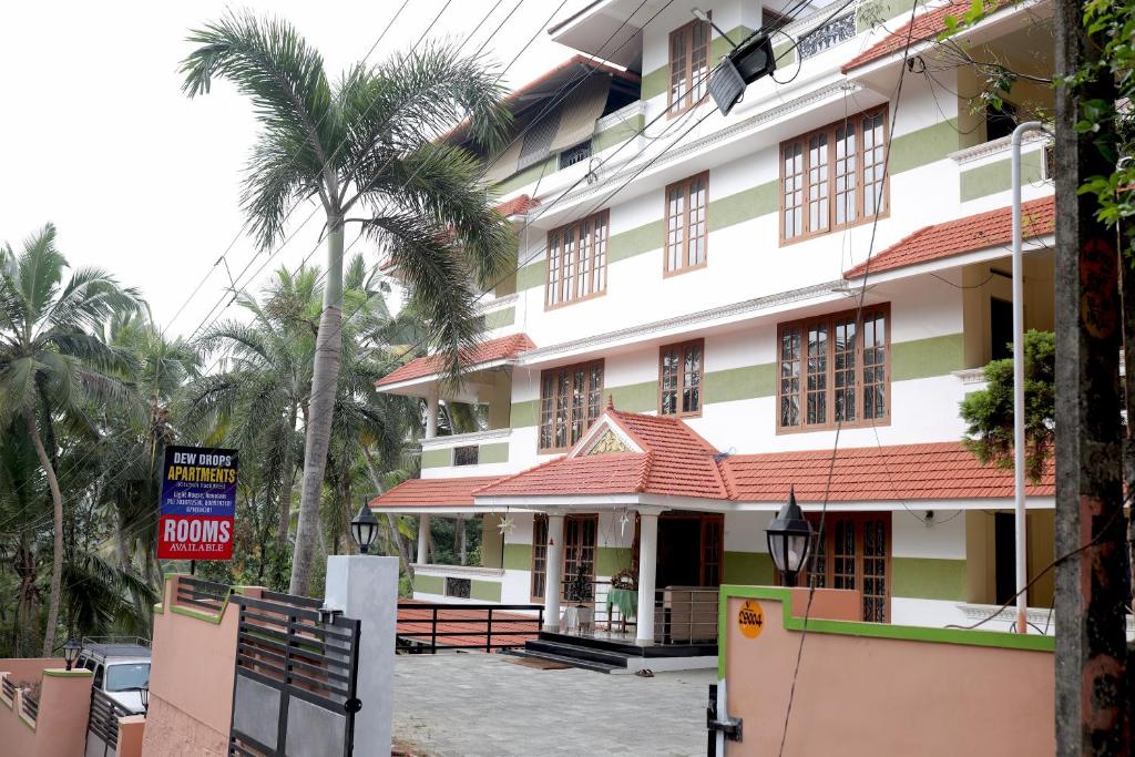 a building with a palm tree in front of it at Dew Drops Inn kovalam in Kovalam