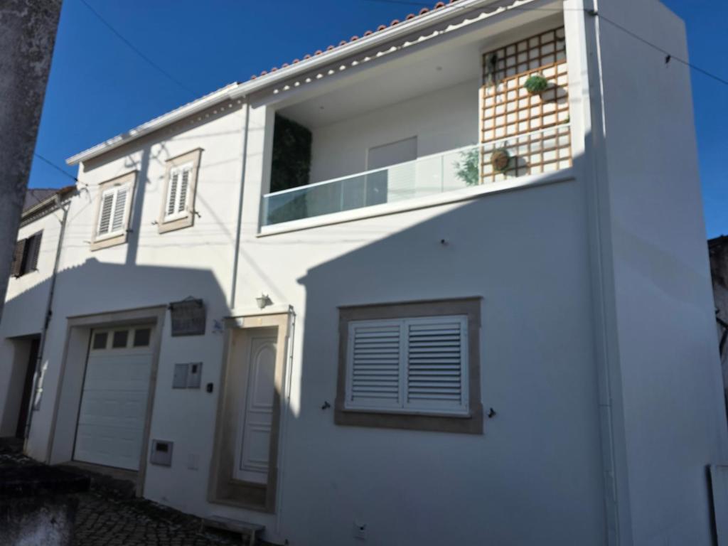 a white house with a balcony on the side of it at Chez Gilbert-Alojamento Local in Alqueidão da Serra