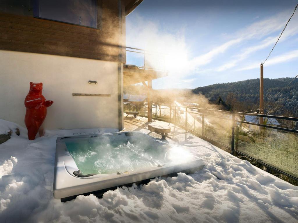 a hot tub sitting on top of a snow covered balcony at Chalet L'Ursus - OVO Network in Gérardmer