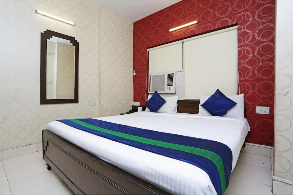 a bedroom with a large bed with blue and green pillows at Bengal Inn in Kolkata