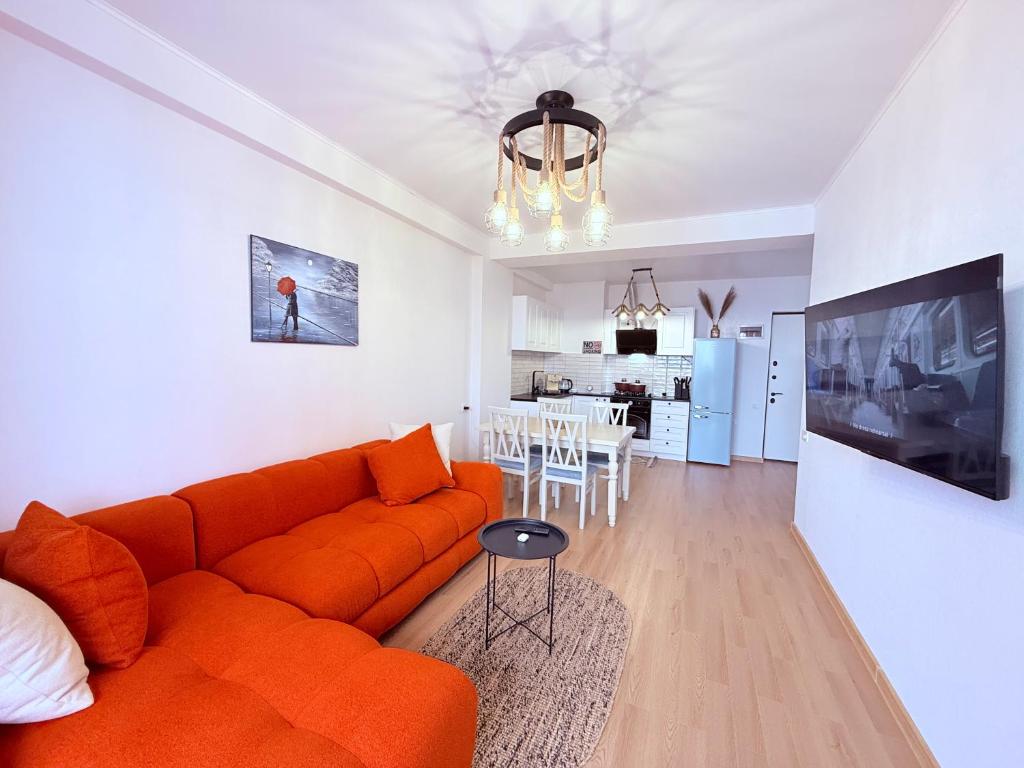 a living room with an orange couch and a kitchen at Likas cozy corner in Tbilisi City