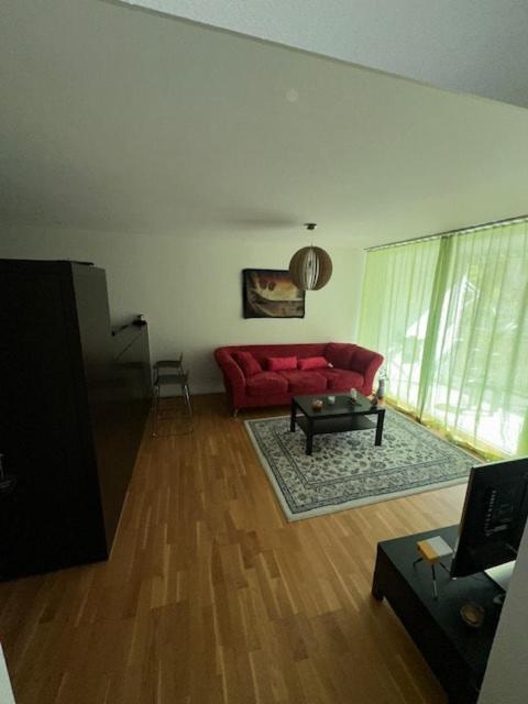 a living room with a red couch and a table at A room in semi shared flat in Wallisellen