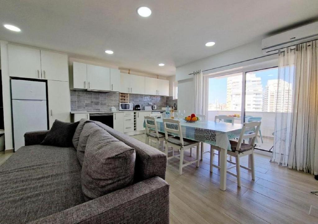 a living room with a couch and a table and a kitchen at Blue Sun Armação in Armação de Pêra