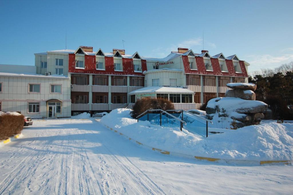 a parking lot covered in snow in front of a building at Алма Ата in Borovoye
