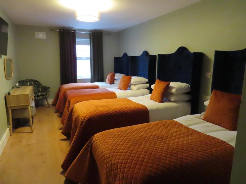 a room with four beds with orange comforters at The Stable Loft at Troysgate in Kilkenny
