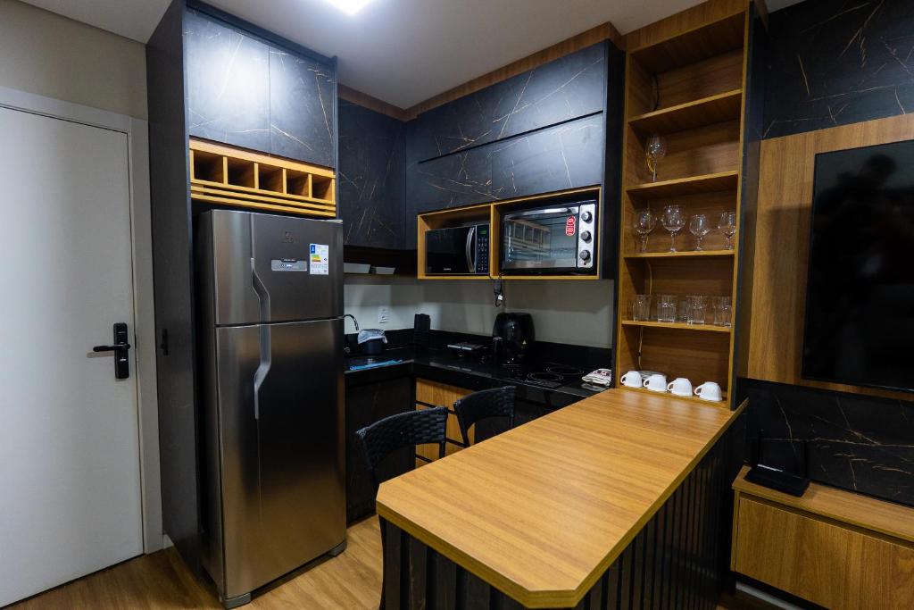 a kitchen with black cabinets and a refrigerator and a table at Flat exclusivo Studio Cuiabá 1211 in Cuiabá