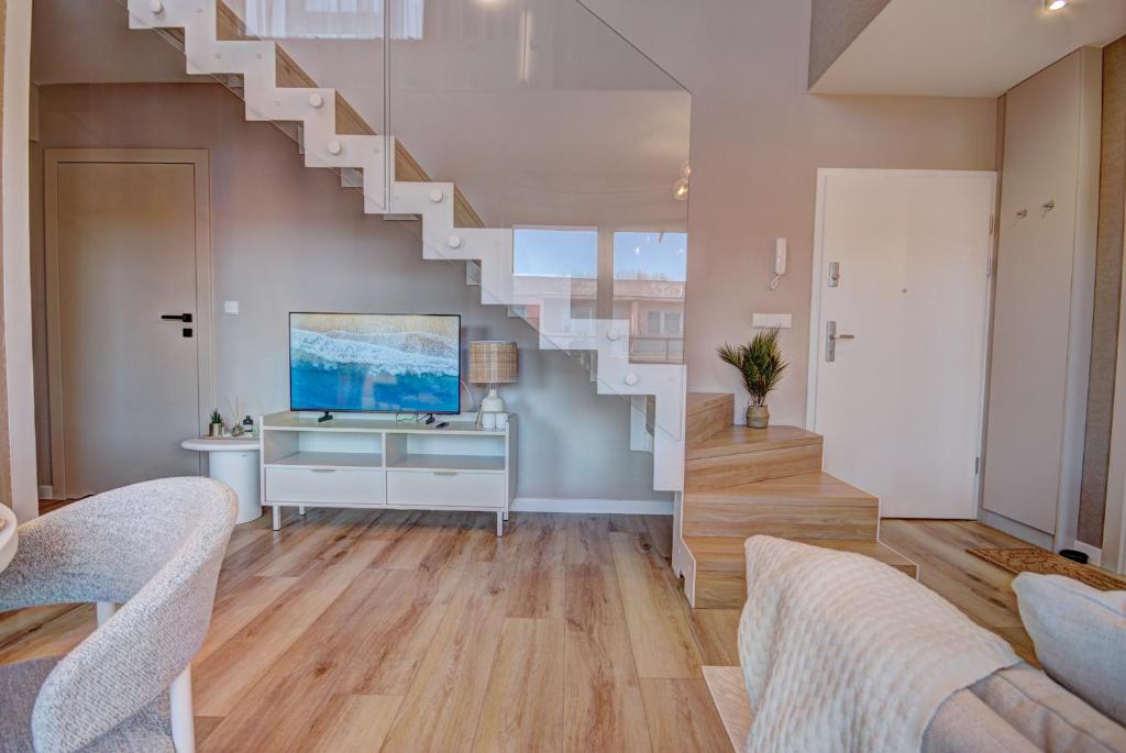 a living room with a staircase and a television at HelApart - Casa Baia in Hel
