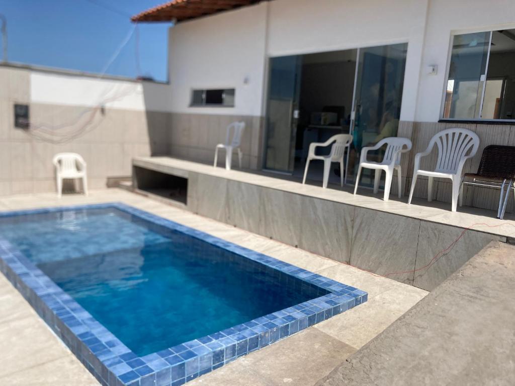 a swimming pool in a house with chairs and a kitchen at Casa em clube in São José de Ribamar