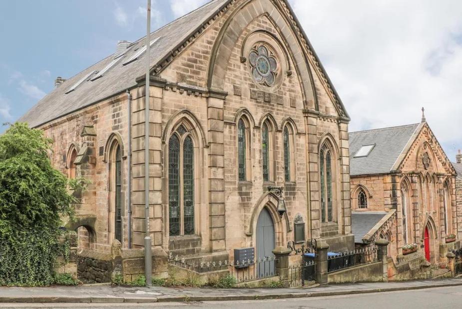 a large stone church with a clock on it at 1885 The Retreat in Matlock
