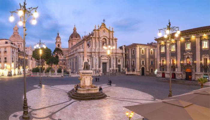 a large building with a fountain in the middle of a courtyard at Downtown Living in Catania