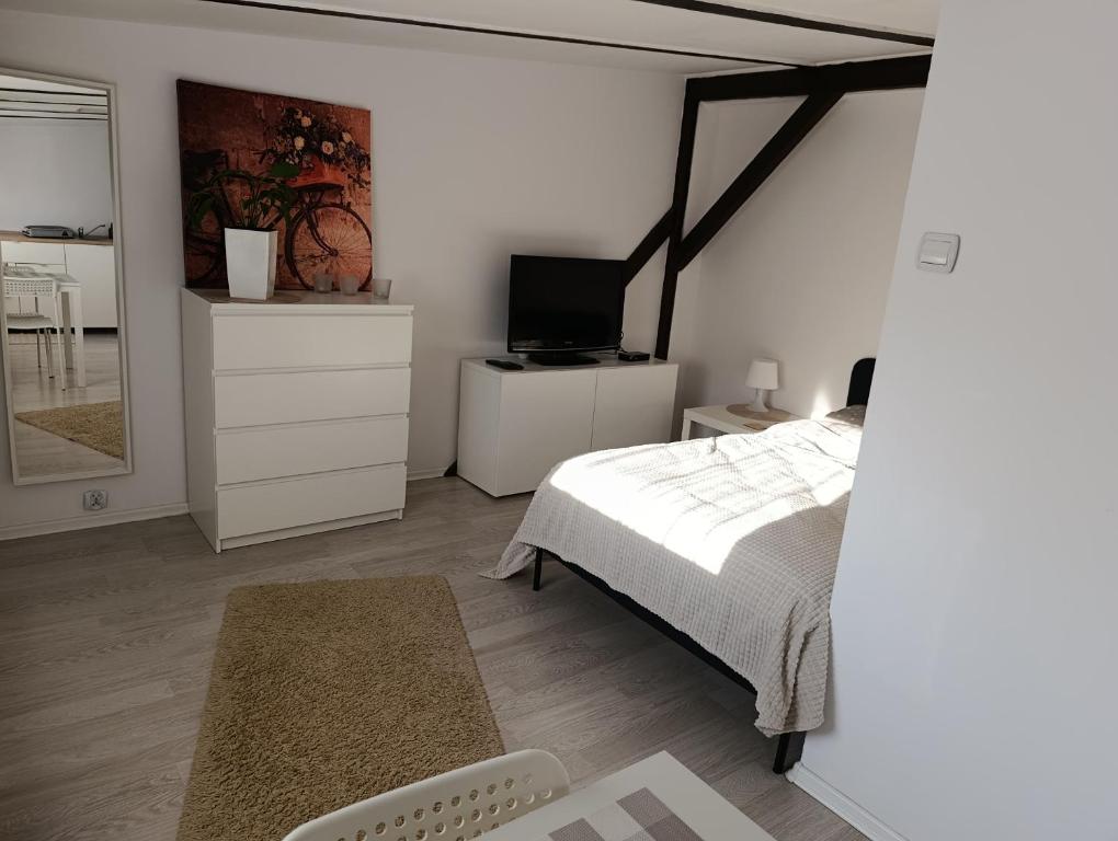 a white bedroom with a bed and a tv at Apartament Mariacka in Bydgoszcz