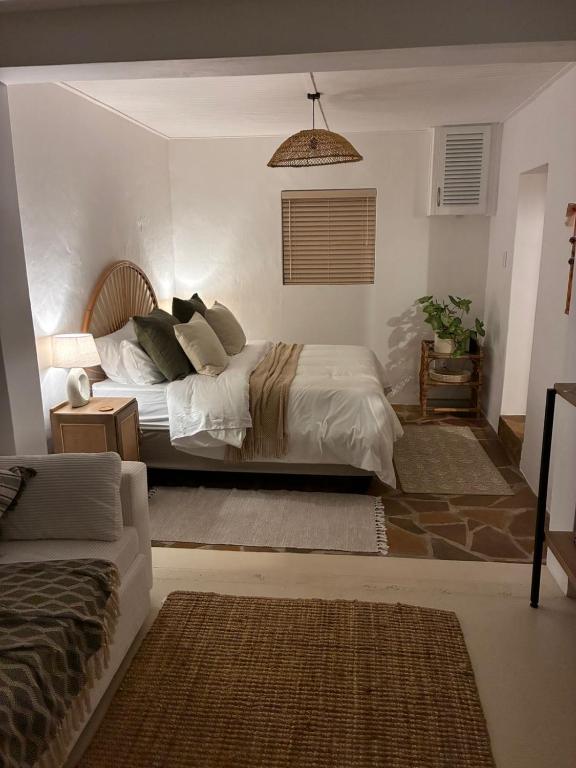 a bedroom with a bed and a couch at Seaside Garden Cottage Schoenmakerskop in Gqeberha