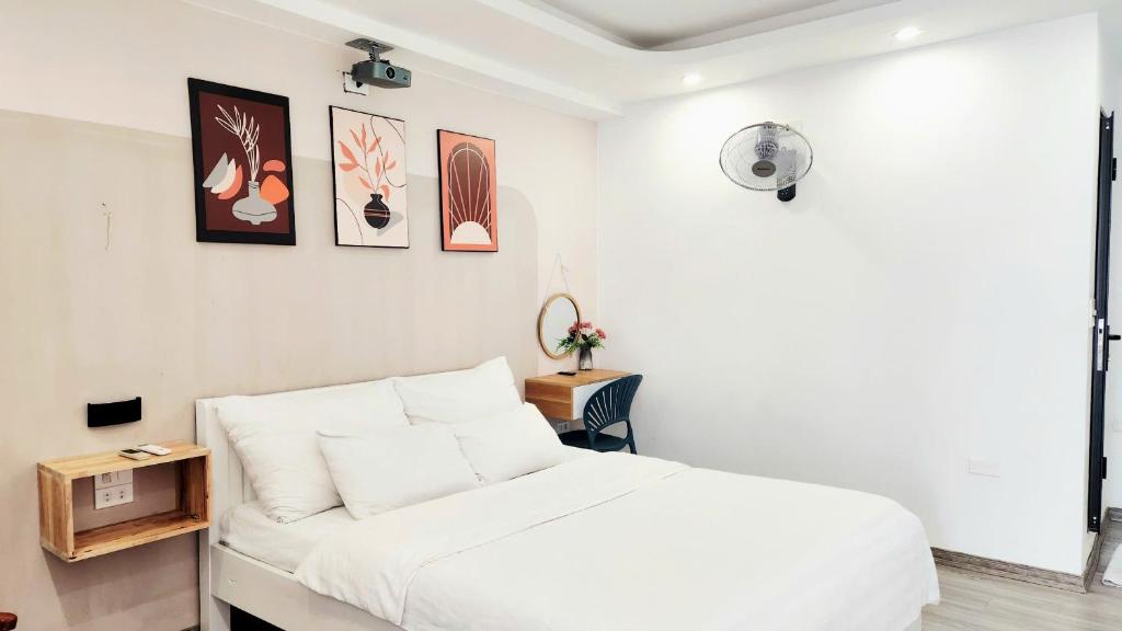 a white bedroom with a bed and a table at Khách Sạn Diamond Hotel Văn Giang Hưng Yên in Cửu Cảo