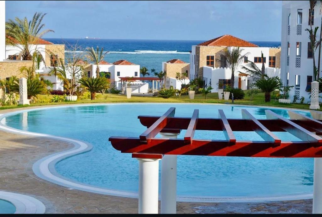 a pool with a red bench in front of a building at Zuri's Beachfront Bliss, With Beach Access -Sultan Palace in Mtwapa