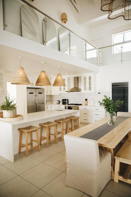 a white kitchen with a wooden table and chairs at White Wicker House in Langebaan